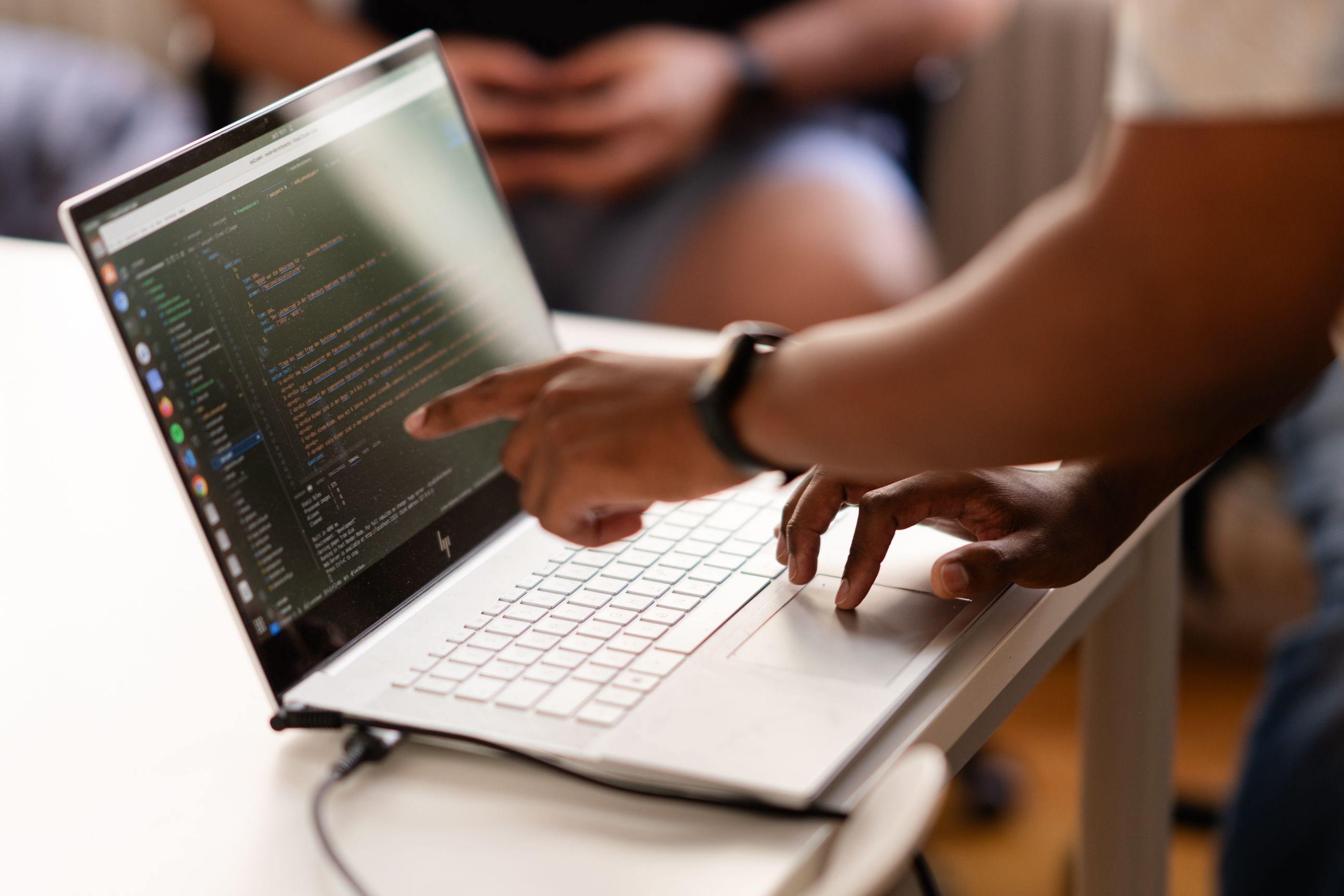 A developer pointing on a screen of a laptop with code.