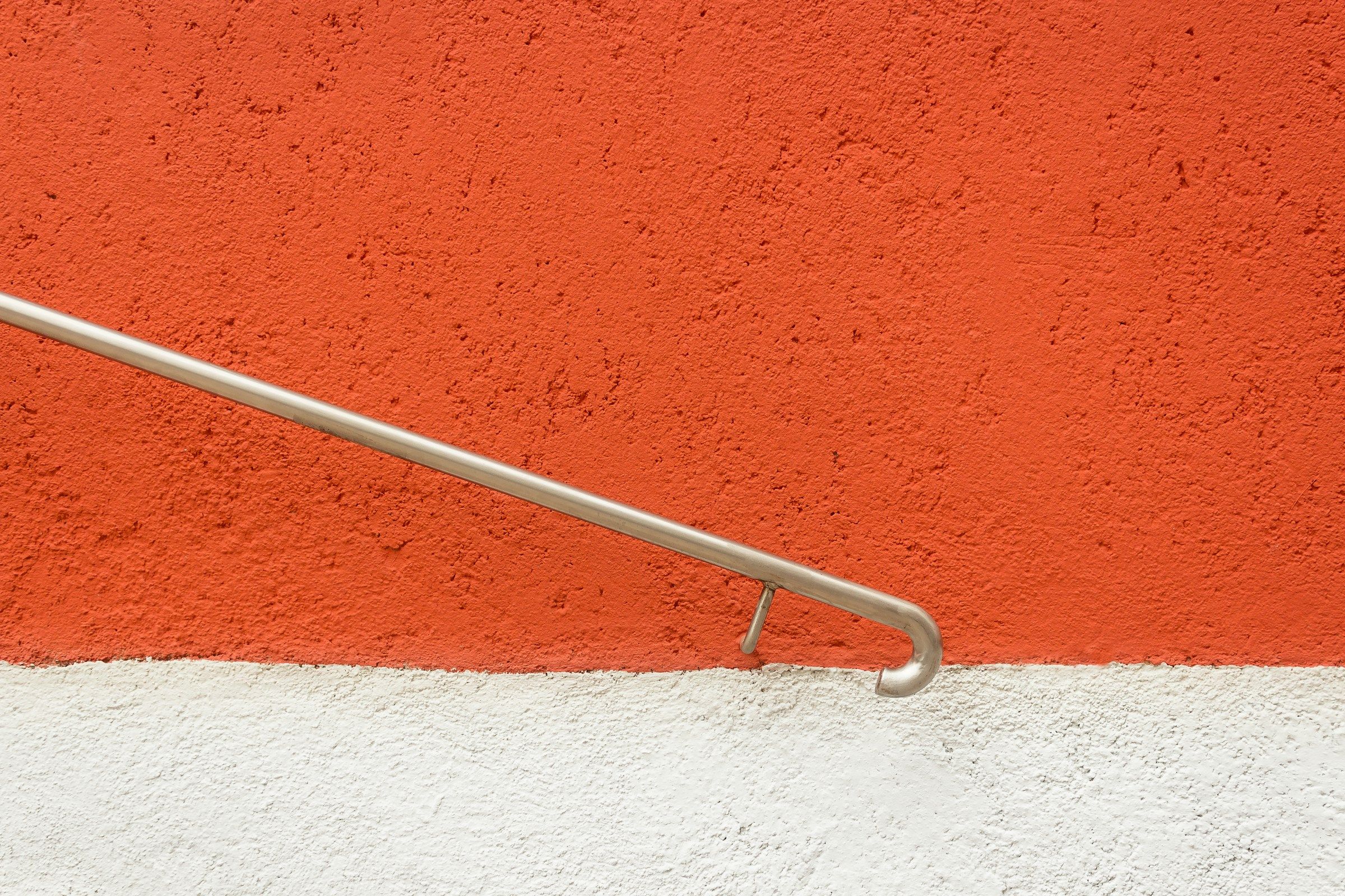 Metal handrail against an orange and white wall